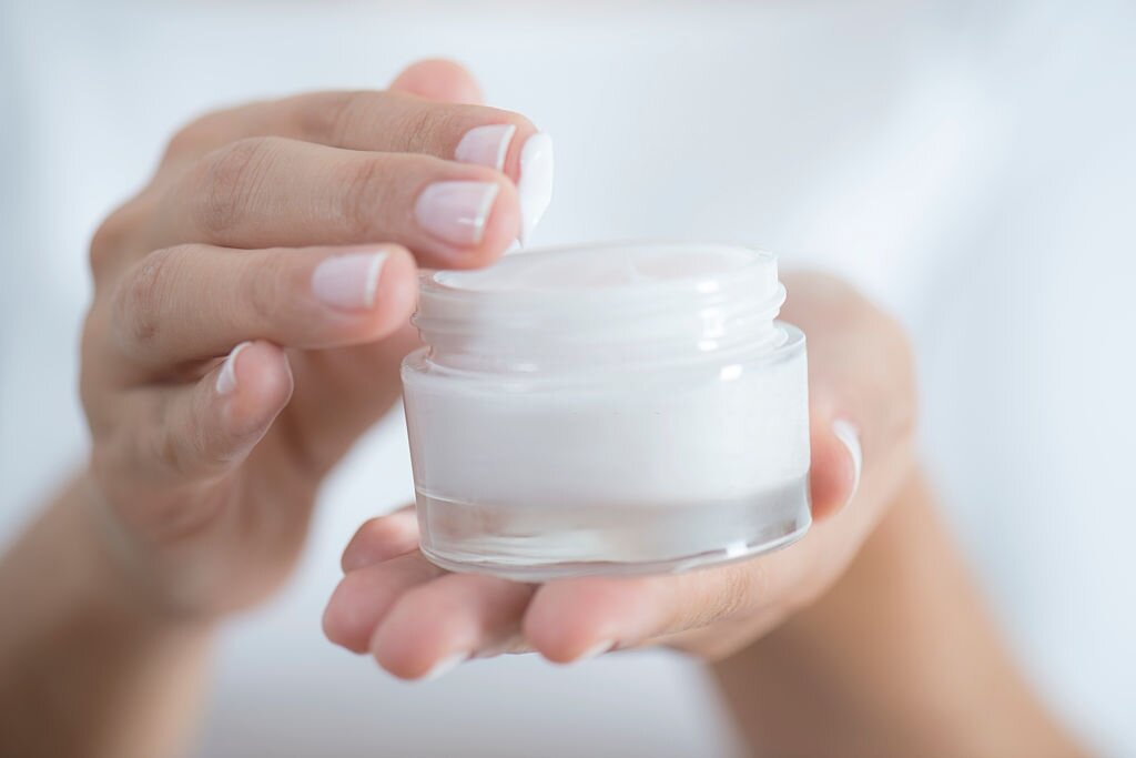 Female hand holding moisturizer in hand, horiztonal
